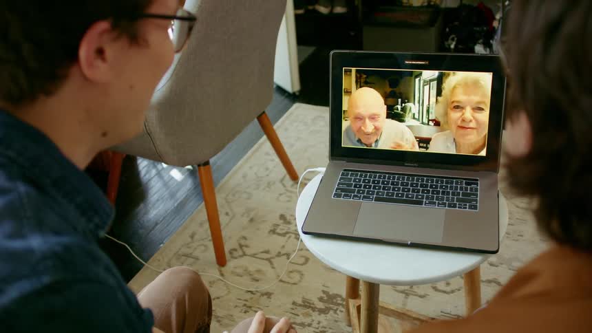 Young couple on a video call with grandparents on a laptop at home