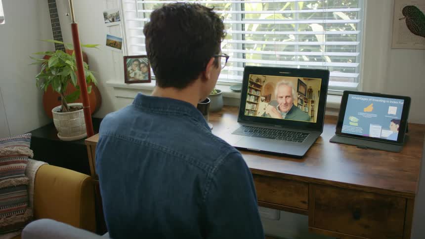 Man talks to another via video call on laptop while drinking from a coffee mug