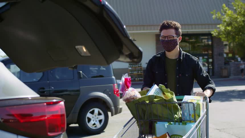A man unloads his groceries into the car