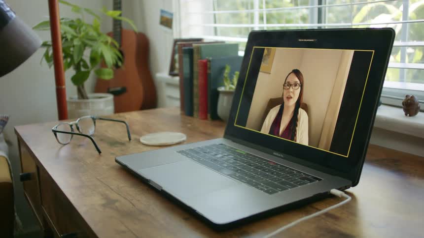 A person sits in front of a laptop having a video call with a woman