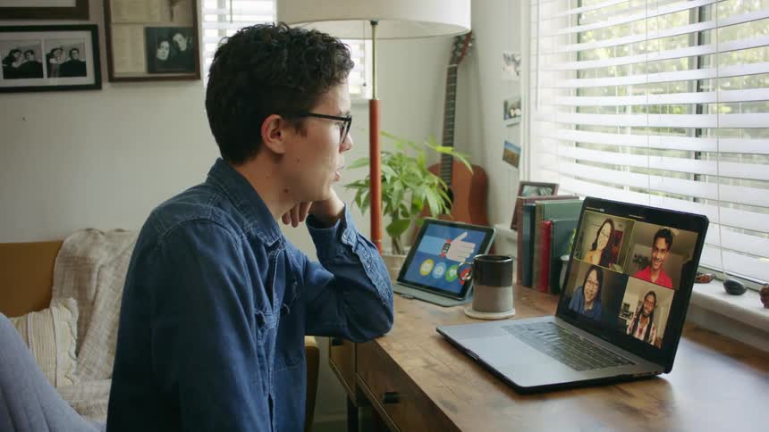 Young man in a video call with friends on a laptop at home