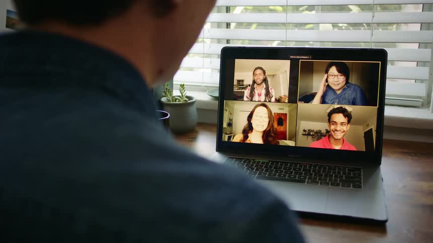 A man is involved in a video conference with four other people with his laptop computer