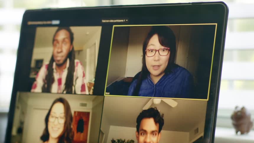 Four people video chat together on the screen of a laptop