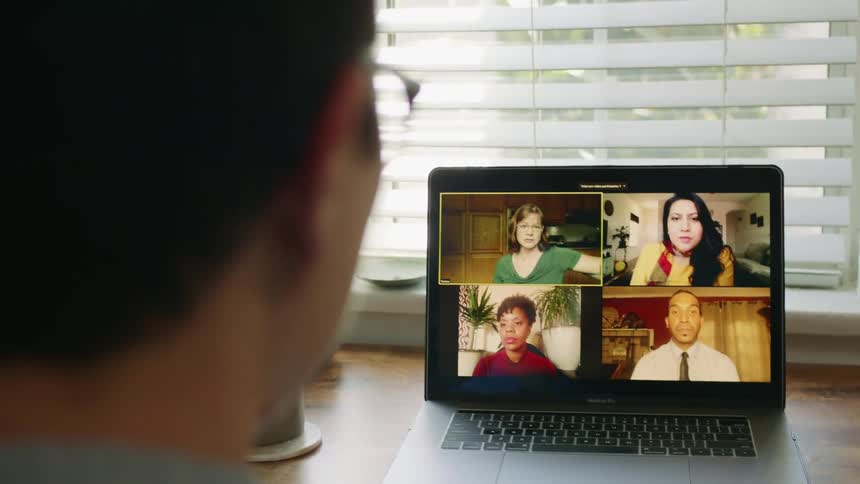 A man talks with his coworkers on a video call from home