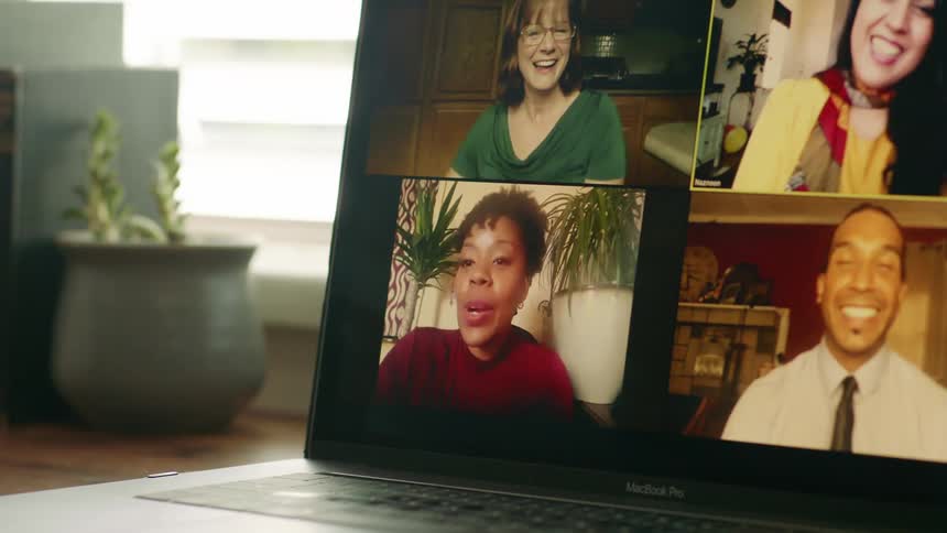 A laptop in a home with four people on it video chatting