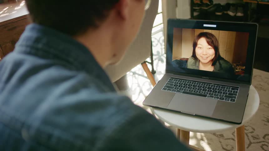 A person sits in front of a laptop having a video call with a woman