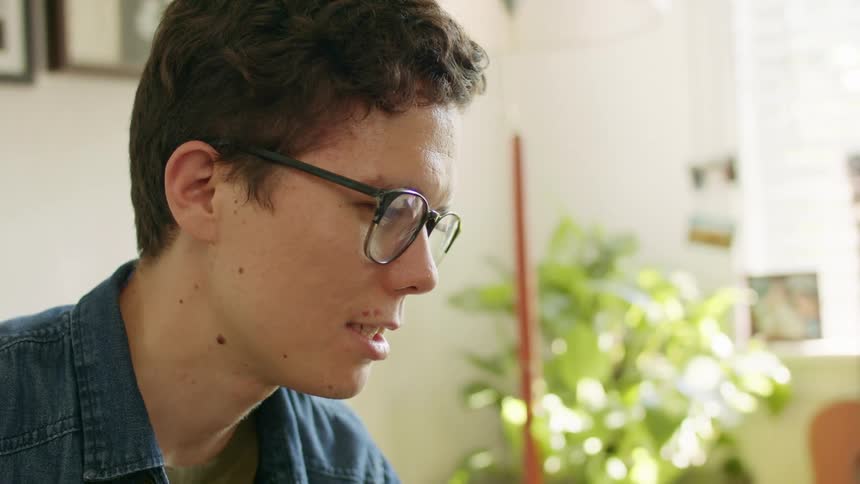 A young man at home nods his head as he talks