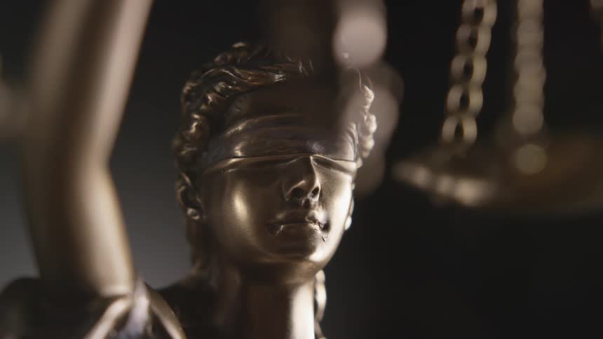 Bronze statue of lady justice on a dimly lit room