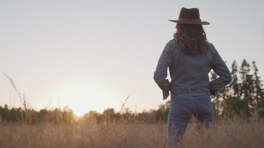 A woman is standing outdoors at dusk