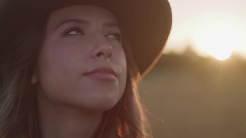 A woman is standing outdoors at dusk