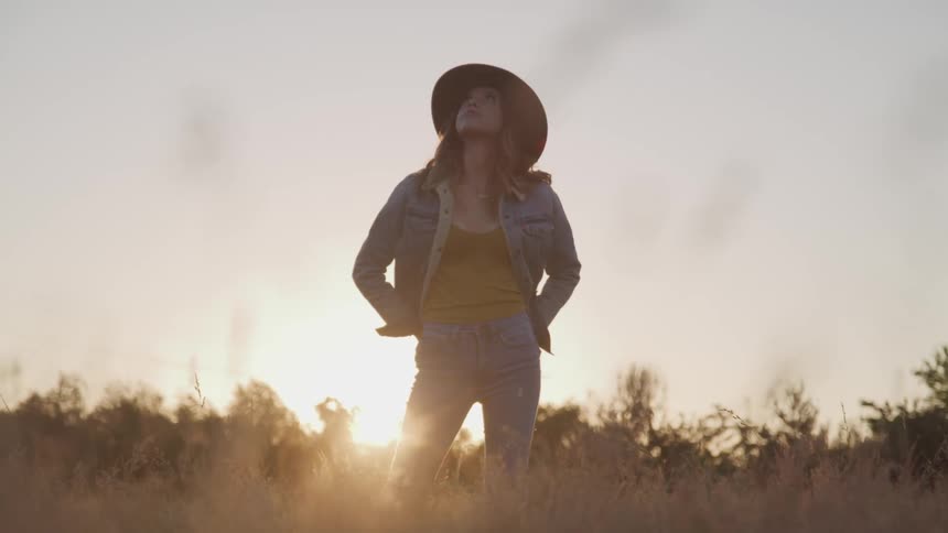 A woman is standing outdoors at dusk