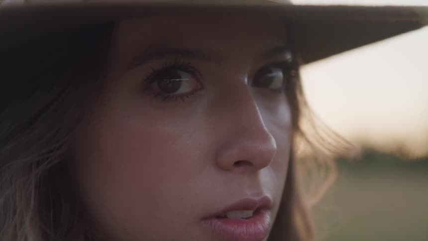 A woman is standing outdoors while wearing a sunhat