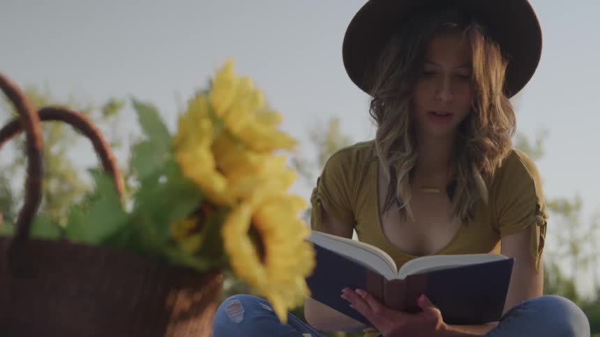 A woman is reading a book outdoors