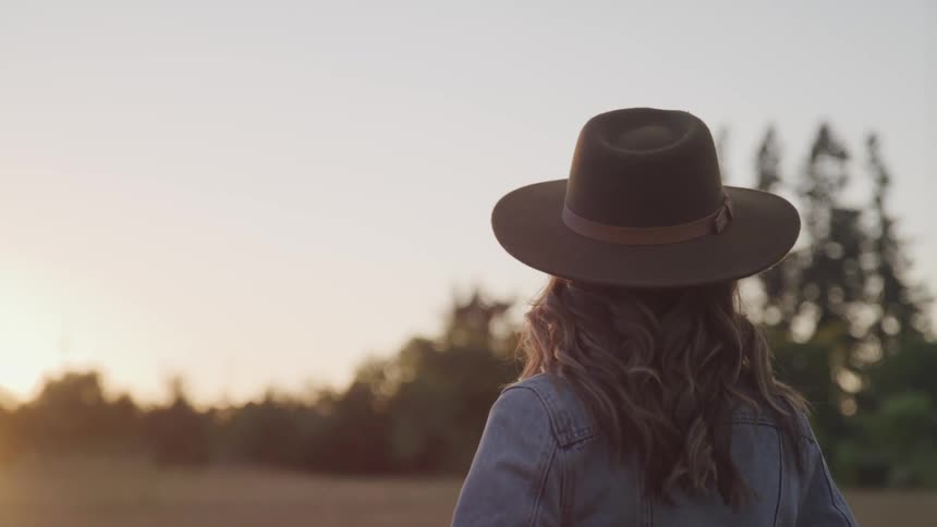 A woman is standing outdoors at dusk