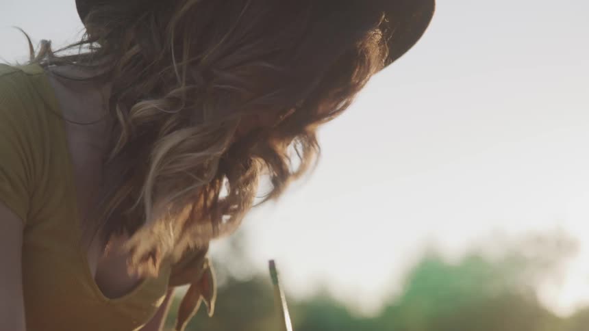 A woman is sitting outdoors and writing with a pencil
