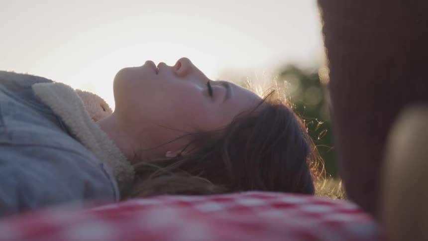 A girl is resting on a blanket outdoors