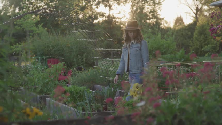 A woman walks through a garden while carrying a bouquet in her purse