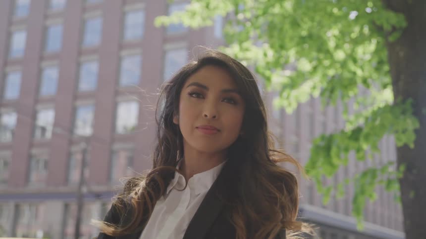 Beautiful long haired business woman standing in front of a building in the city at day