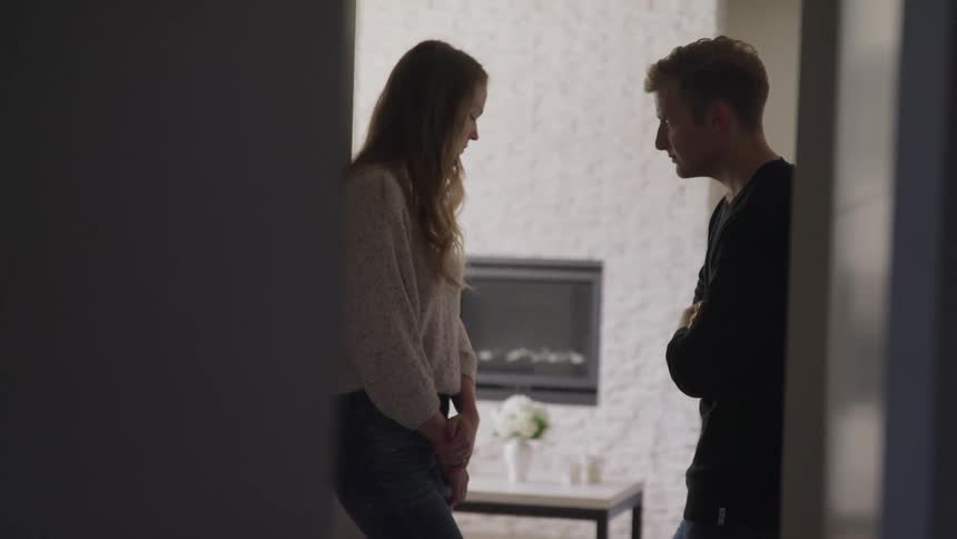 A man and a woman standing by a doorway with a table in the background