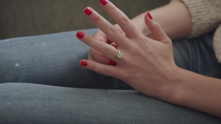 A woman sits and fiddles with a nice engagement ring on her finger
