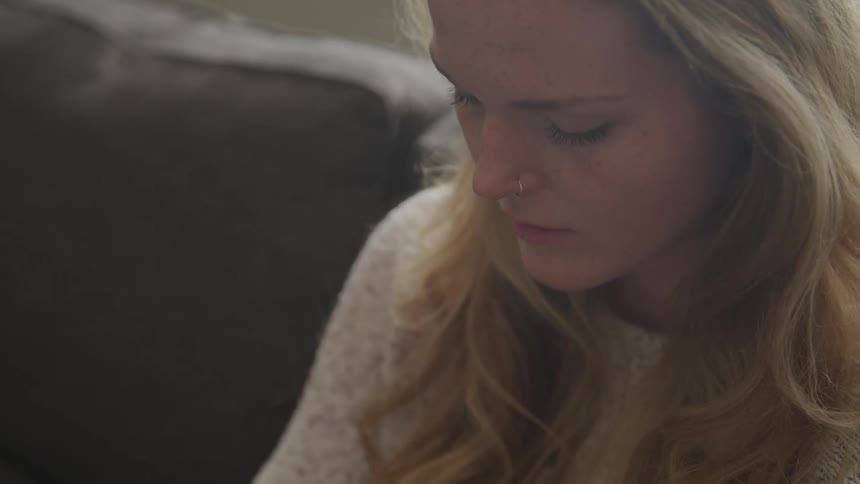 A woman with a sweater sitting on a couch
