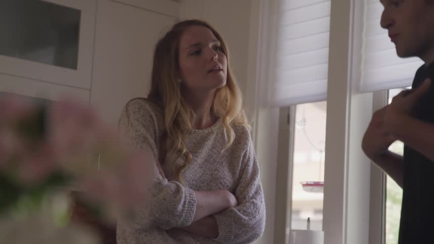 A man and woman standing in a kitchen and talking