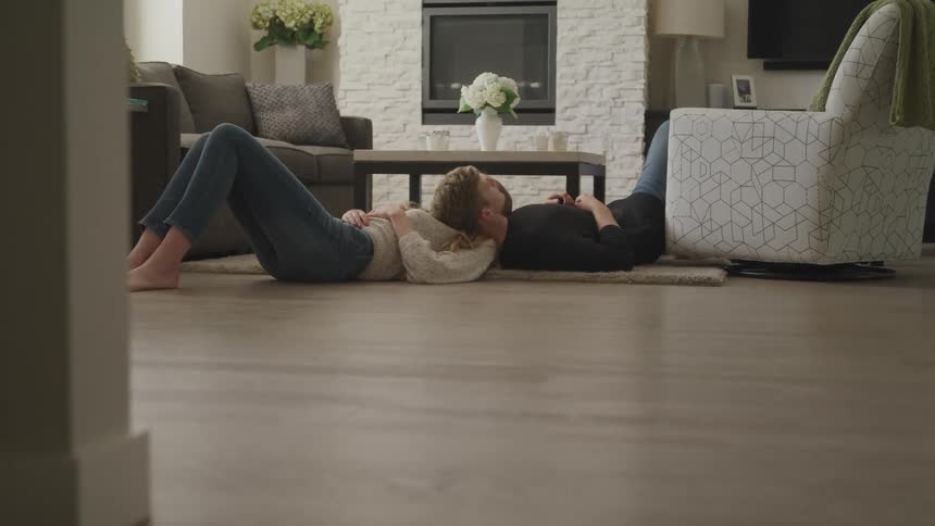A man and woman are laying on the ground indoors
