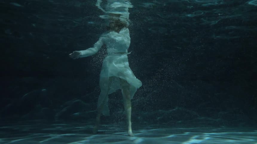 A woman is floating in the water wearing a white dress