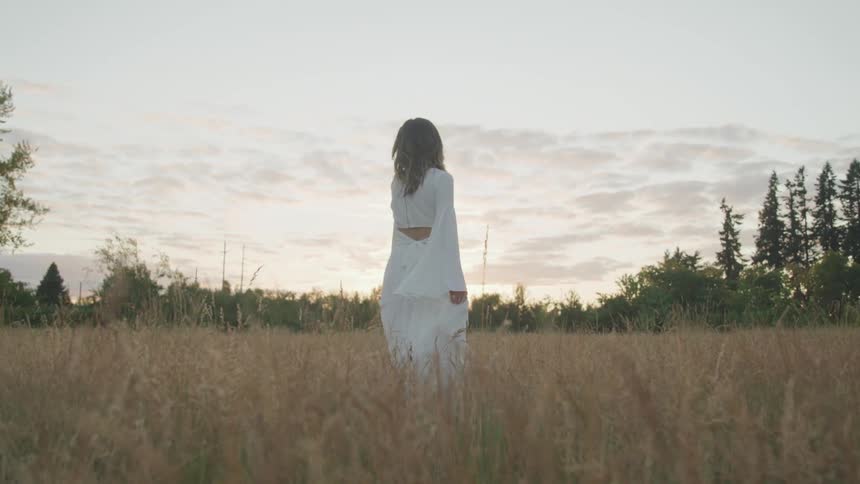 A woman is walking through a grassland area