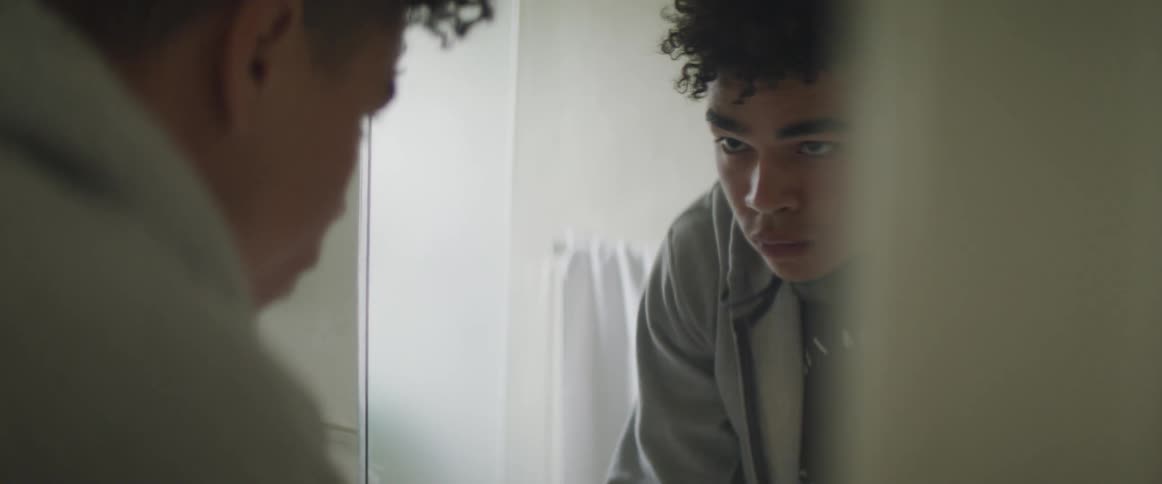 A teenage boy at home looks up and looks in a mirror