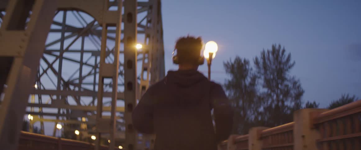 A man is jogging on a bridge at night