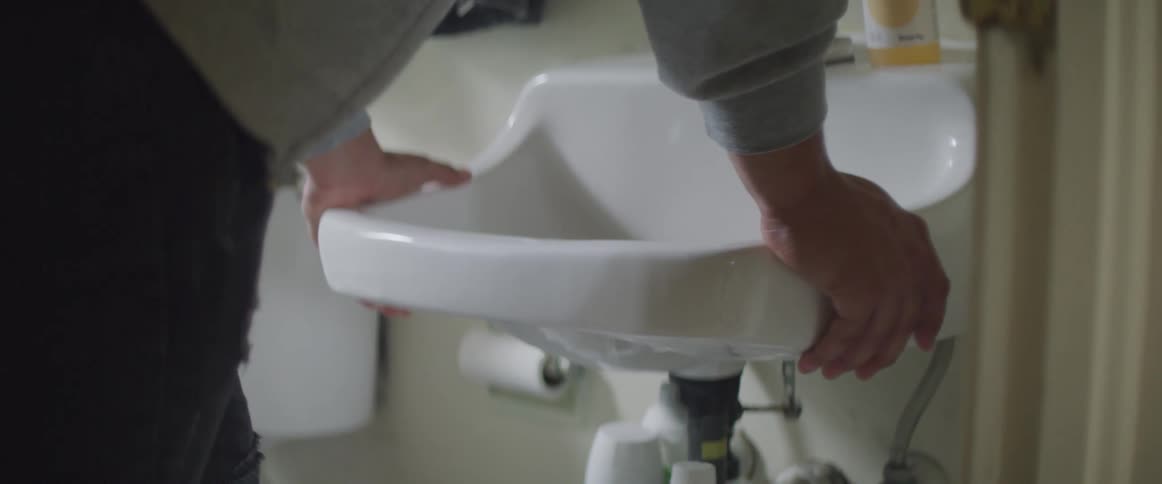 A man leans against a sink in a bathroom during the day