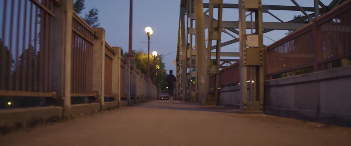 A person running down a sidewalk at dusk
