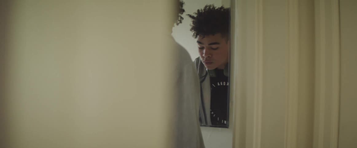 Teenage boy looks at himself in bathroom mirror
