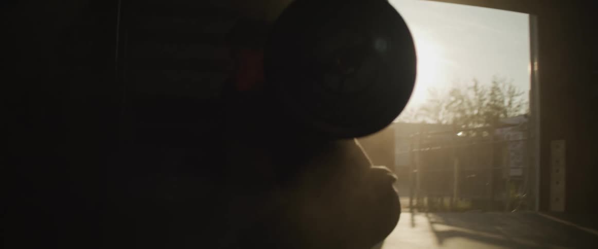 The sun shines in to a garage where a person squats with weights