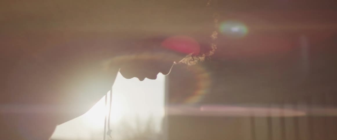 A person with a sweatshirt in a room with a doorway and the sun in the background