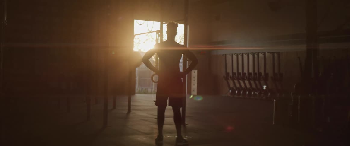 A man is standing in the dark gym