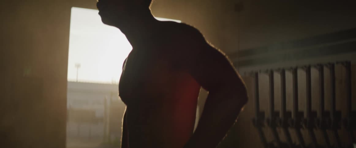 A man is standing in a gym at dusk