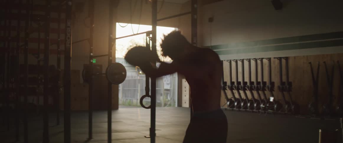 A teenage boy slams a medicine ball down as he exercises