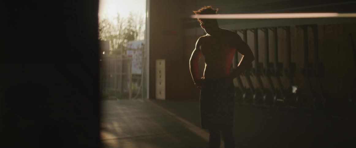 A man standing in a room with a doorway and the sun in the background