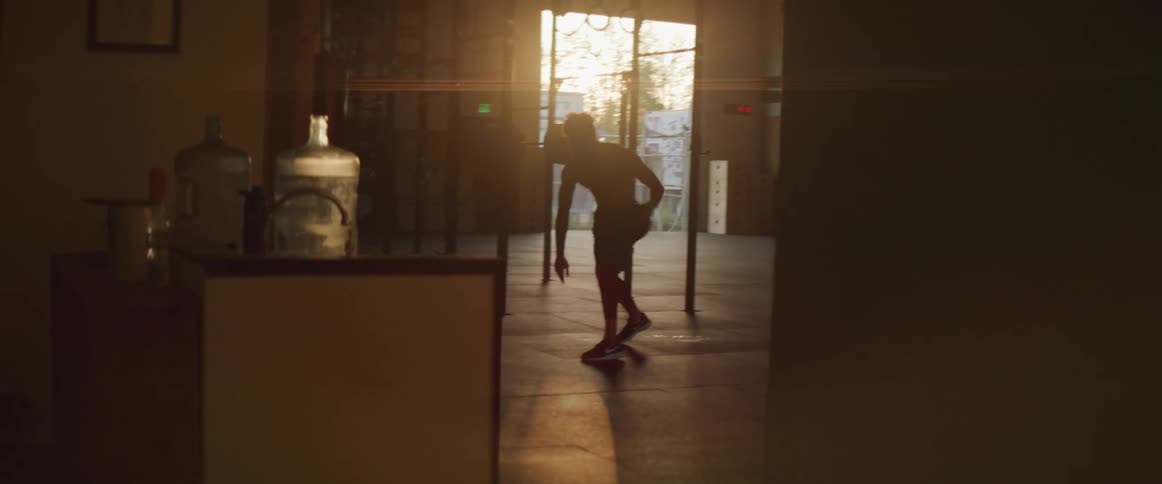A silhouette of a man dribbling a basketball with a doorway in the background