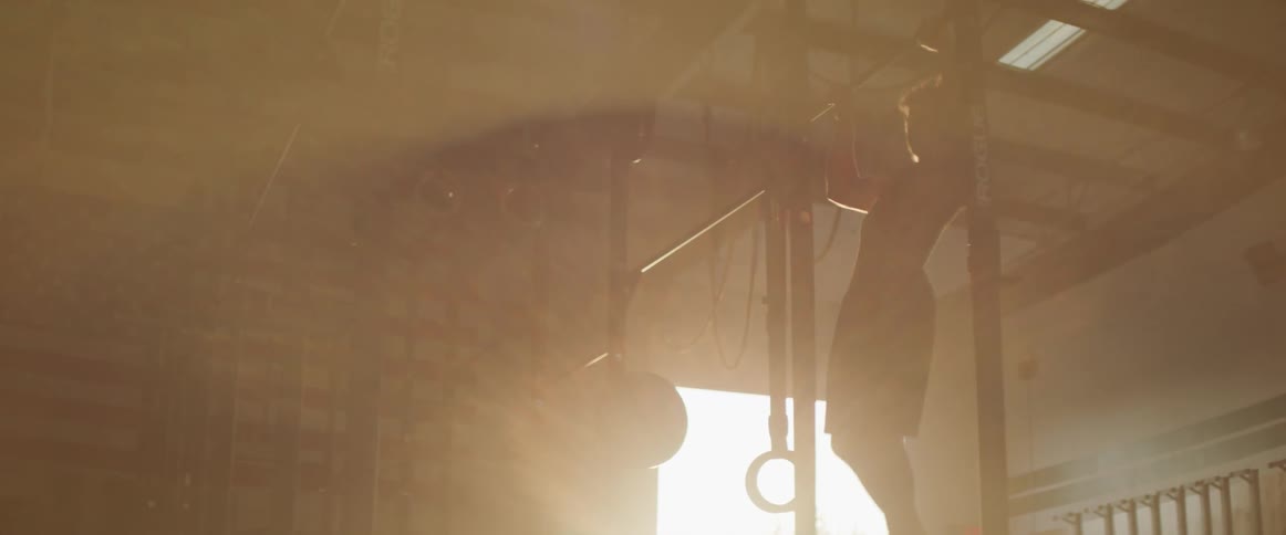 A teenage boy does pull ups inside a building