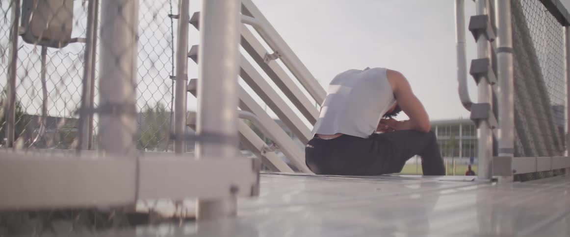 Young fit muscular man resting on the stairs outdoors