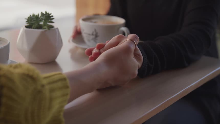 Couple holding hands on table with coffee