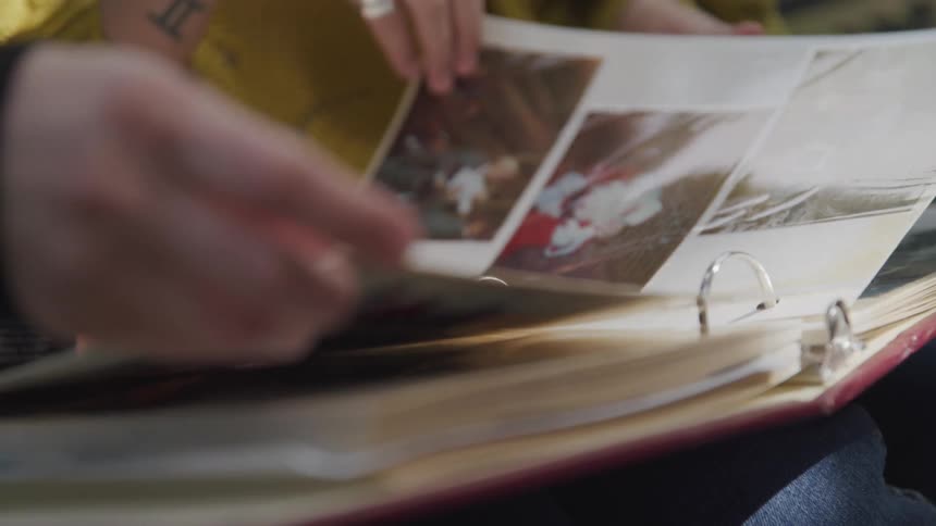 Two women look at a book filled with photographs