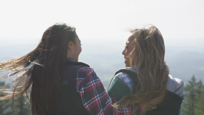 Two teenage girls laughing together outside