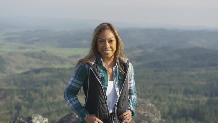 Woman poses near edge in front of landscape covered in fog
