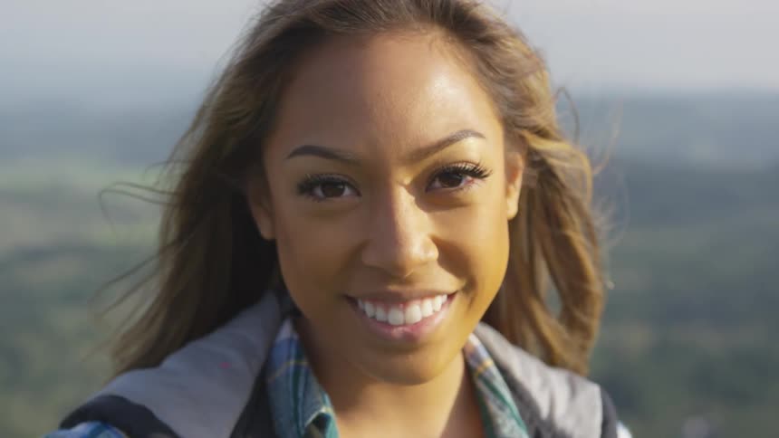 A woman is standing outdoors and smiling