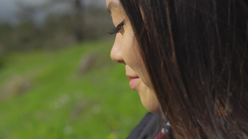 A young woman on the grass outside with her eyes closed