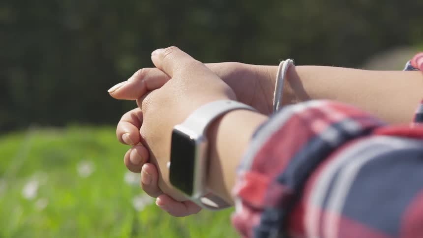 Hands of a young woman on a grass field at day